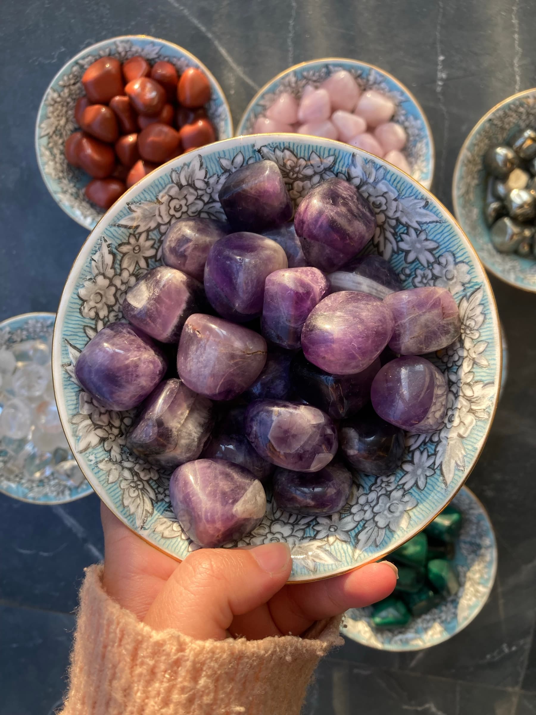 Consecrated amethyst tumbles held in gentle hands